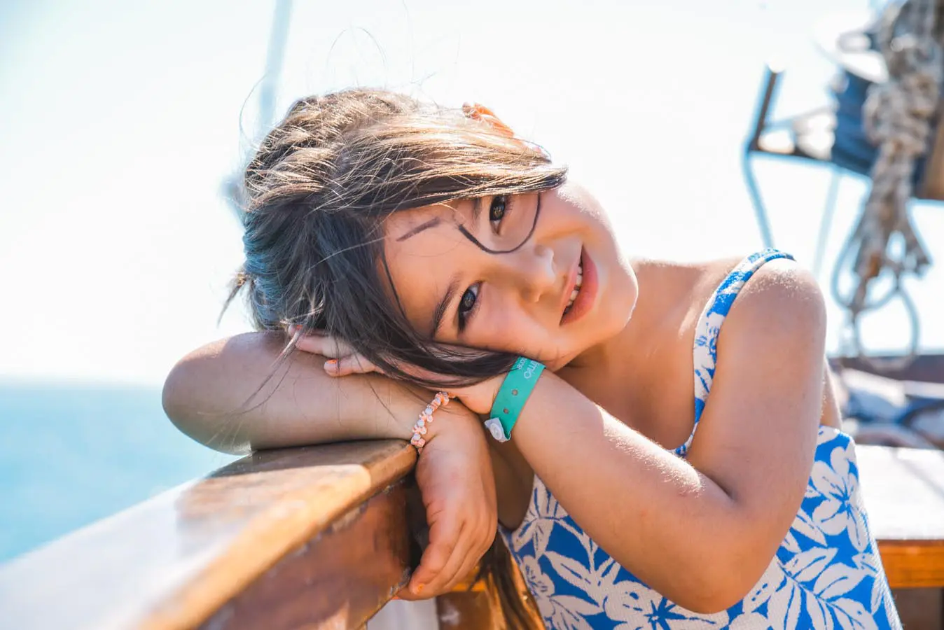 Una bambina con la benda da pirata disegnata sul viso, appoggiata alla barca davanti al mare
