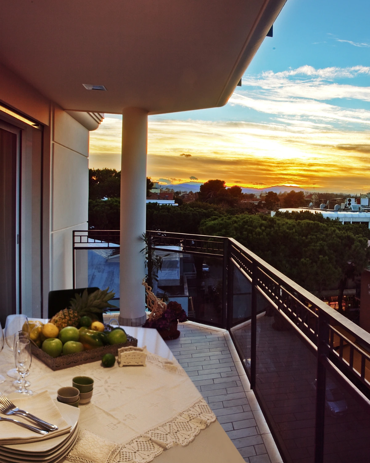 Il balcone di un appartamento al tramonto, con la tavola apparecchiata e la frutta