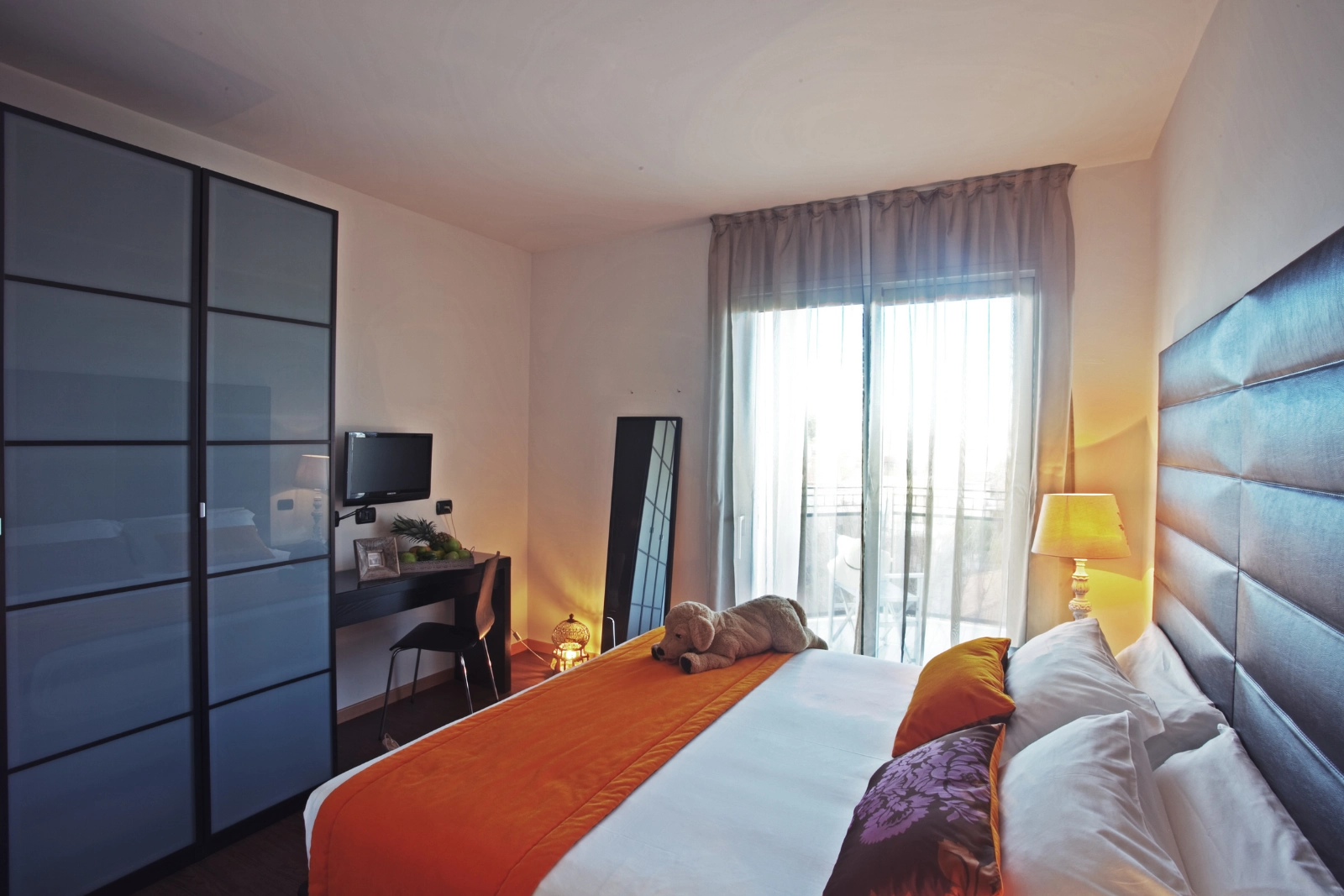 La camera da letto della D-Four Suite, con l’armadio a vetri satinati e la portafinestra sul balcone